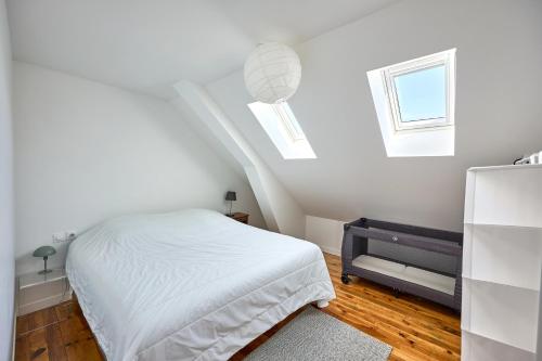 une chambre blanche avec un lit et deux fenêtres dans l'établissement Le Nid Maritime - duplex proche de la plage, à Barneville-Carteret