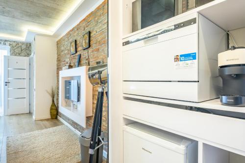 a kitchen with white cabinets and a brick wall at BalatonGardens Apartman in Balatonudvari