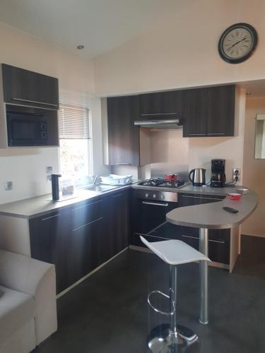 une cuisine avec des armoires noires, une table et une horloge dans l'établissement Mobilhome sur terrain privé, à La Celle-sous-Gouzon