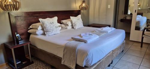 a bedroom with a large bed with white sheets and pillows at Elegant Lodge & Conference Center in Pongola