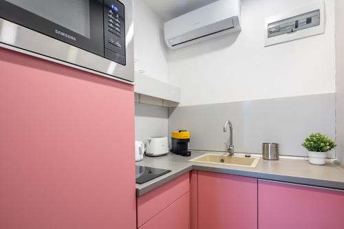 a kitchen with a red door and a sink at BalatonGardens Apartman in Balatonudvari