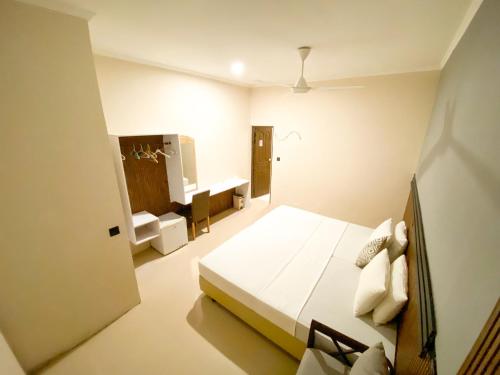 a white bedroom with a bed and a bathroom at Tropika Beach Thulusdhoo in Thulusdhoo