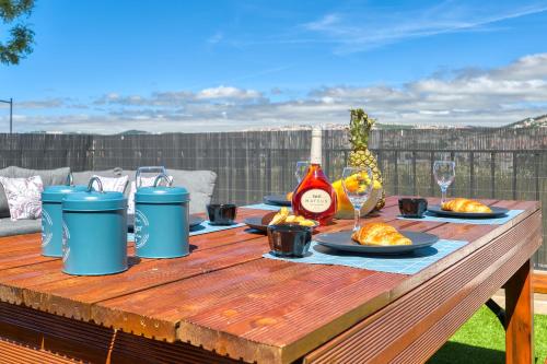 a wooden table with plates of food and a bottle of wine at Vita Portucale ! Santa Clara Terrace & Jacuzzi in Lisbon