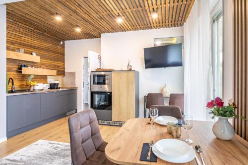 a kitchen and dining room with a table and chairs at BalatonGardens Apartman in Balatonudvari