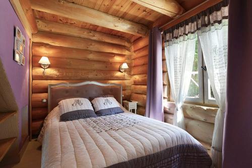 une chambre avec un lit dans une cabane en rondins dans l'établissement Cabane de Rêve, à Montmurat