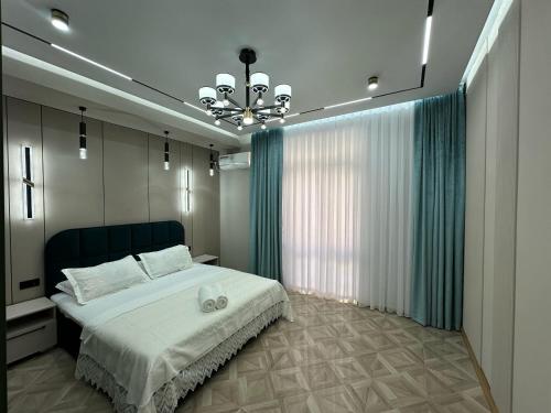 una camera da letto con un letto grande e un lampadario di ЖK Керуен Сарай a Türkistan
