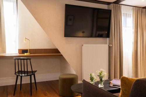 a living room with a table and chairs and a tv at Hotel Le Colombier in Obernai