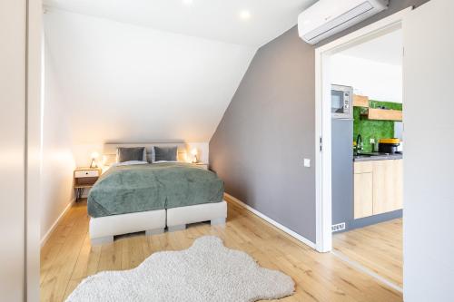 a white bedroom with a bed and a kitchen at BalatonGardens Apartman in Balatonudvari