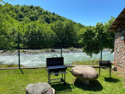 a yard with two chairs and a bench and a fence at River house in Ozurgetʼi