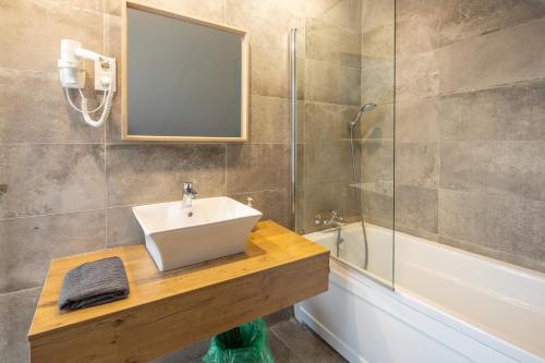 a bathroom with a sink and a shower and a mirror at BalatonGardens Apartman in Balatonudvari