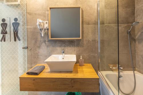 a bathroom with a sink and a tub and a mirror at BalatonGardens Apartman in Balatonudvari