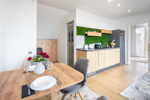 a kitchen and dining room with a wooden table and chairs at BalatonGardens Apartman in Balatonudvari