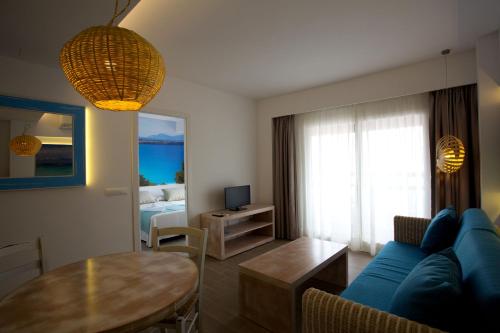 a living room with a blue couch and a table at Apartamentos Pou Des Pujols in Es Pujols