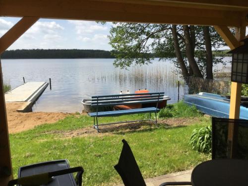 a bench on the shore of a lake with a boat at Feriengrundstück Direkt Am See Für 2 Erwachsene Und 3 Kinder in Dabel