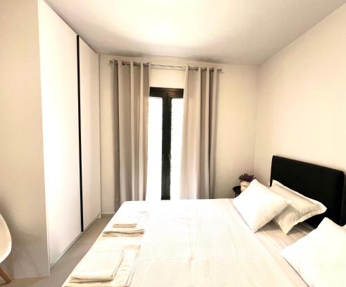 a bedroom with a large white bed with a window at Farm House Near Of Merhia Beach In Mykonos in Merchia Beach