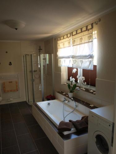 a bathroom with a tub and a washing machine at Feriengrundstück Direkt Am See Für 2 Erwachsene Und 3 Kinder in Dabel