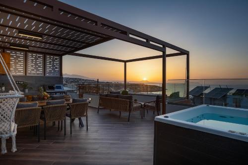 a house with a hot tub on a deck with the sunset at Amaltheia Luxury Residence in Rethymno Town