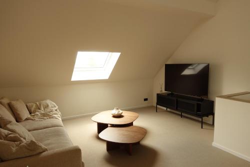 a living room with a couch and a tv at La Barzalière in Chimay