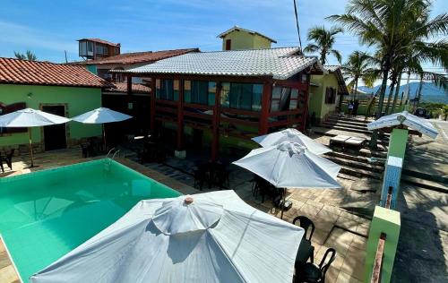a pool with umbrellas next to a building at Pousada Aconchego de Maricá in Maricá