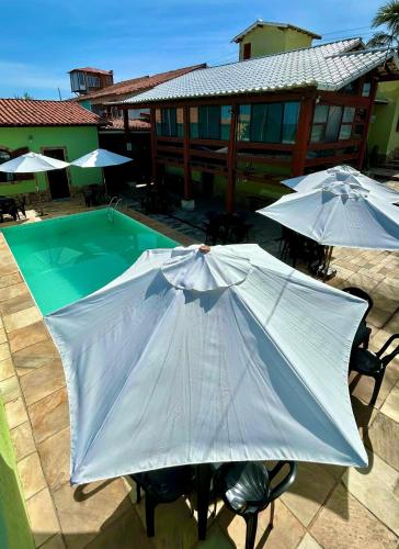 two tables with umbrellas next to a swimming pool at Pousada Aconchego de Maricá in Maricá