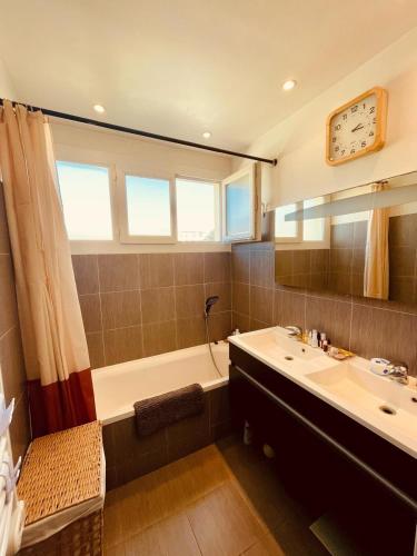 La salle de bains est pourvue d'une baignoire, d'un lavabo et d'un réveil. dans l'établissement Bel Appartement lumineux avec balcon, au Cannet