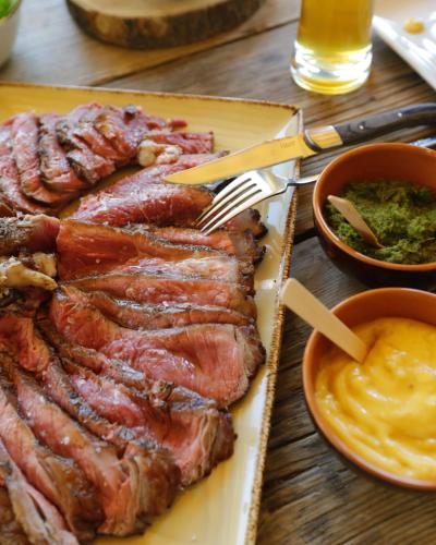 a plate of meat on a table with a fork and dip at Asolo Norah's Hill Agri Rooms in Caenere