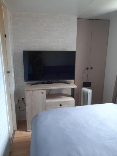 a bedroom with a flat screen tv on a wall at Au petit coin tranquille in Saint-Gobert