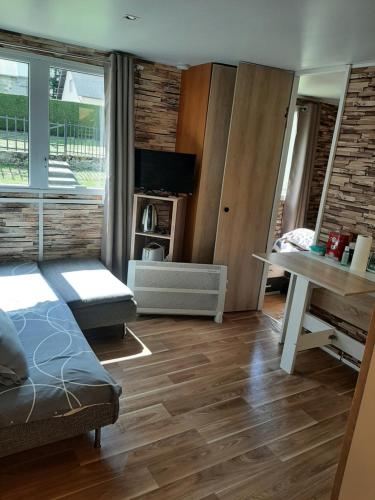 a living room with a bed and a desk at Au petit coin tranquille in Saint-Gobert