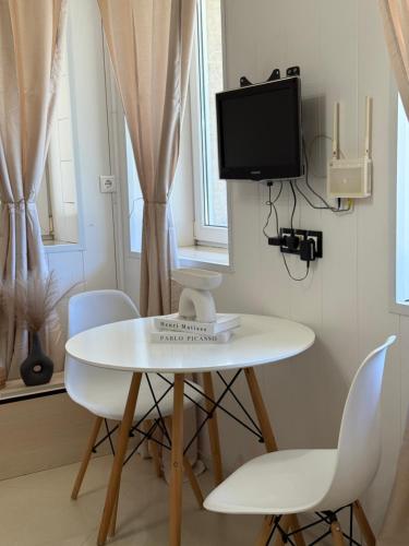 ヴァルナ・シティにあるDayanas Suiteのテレビ付きの客室で、白いテーブルと椅子が備わります。