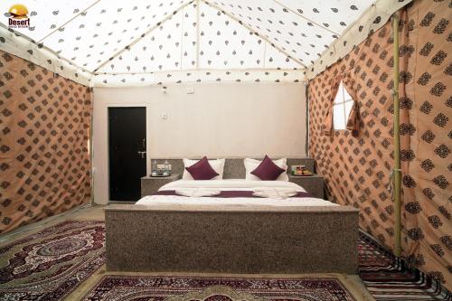 une chambre avec un grand lit dans une tente dans l'établissement Desert Gold Resort Jaisalmer, à Jaisalmer