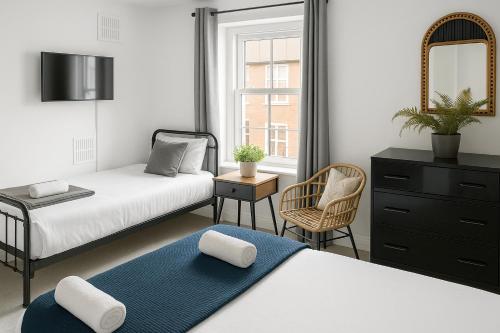 a bedroom with two beds and a mirror and a chair at Morpeth City Centre Apartment in Morpeth