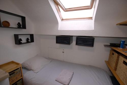 une chambre avec un lit blanc avec une lucarne dans l'établissement Studio gare Viotte et centre ville, à Besançon