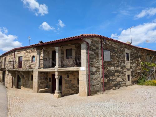 an old stone building with a balcony on it at Casa do Poço in Miranda do Douro