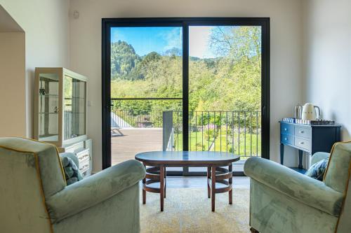 a living room with a table and chairs and a balcony at Casa da Bruma in Furnas