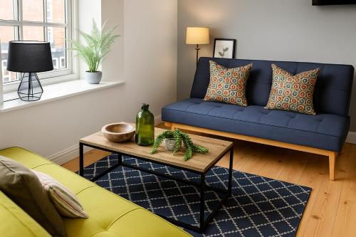 a living room with a blue couch and a table at Morpeth City Centre Apartment in Morpeth