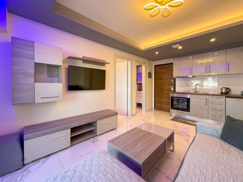 a living room with a couch and a tv and a table at Ilektra Suites by SDR in Paralia Katerinis