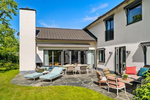 a patio with chairs and tables in front of a house at Luxurious family villa in a unique location in Djursholm