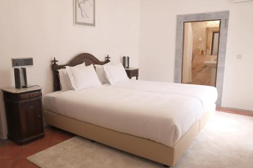 a bedroom with a large white bed and a bathroom at Convento da Orada - Monsaraz in Monsaraz