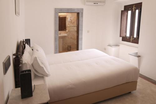 a bedroom with a white bed and a bathroom at Convento da Orada - Monsaraz in Monsaraz