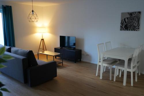 a living room with a couch and a table and a television at Ferienwohnungen Rosengarten in Mommenheim