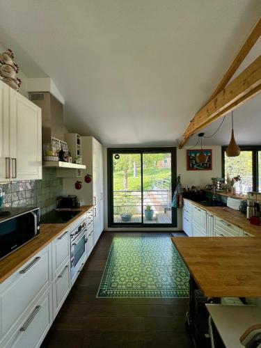 une cuisine avec des placards blancs et une grande fenêtre dans l'établissement Seine Riverside Getaway Ideal for Families near Paris, à Villennes-sur-Seine