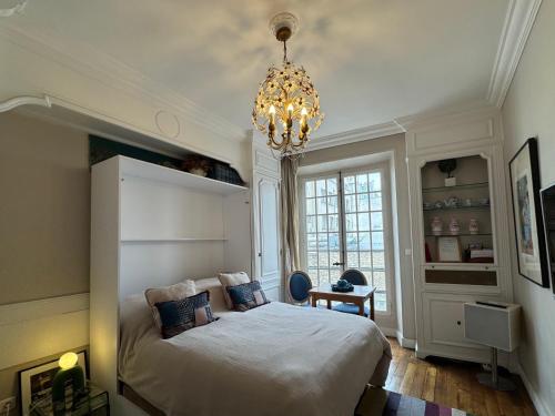 une chambre avec un grand lit et un lustre dans l'établissement Studio de charme au coeur de Paris, à Paris