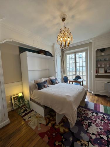 une chambre avec un grand lit et un lustre dans l'établissement Studio de charme au coeur de Paris, à Paris