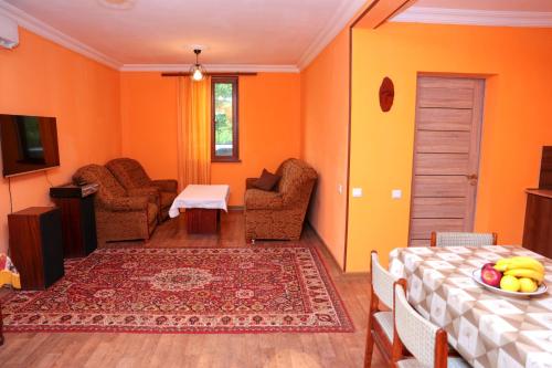 a living room with orange walls and a table and chairs at Stay Hovq in Dilijan