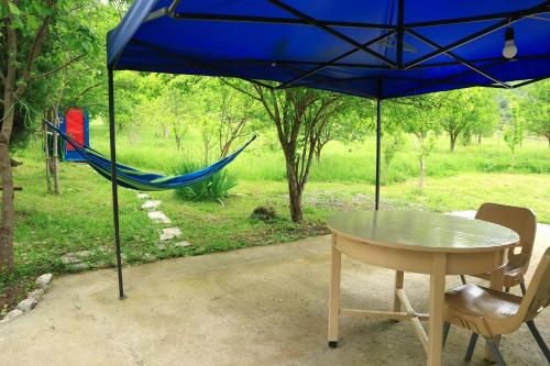 a table and a hammock under a blue umbrella at Stay Hovq in Dilijan