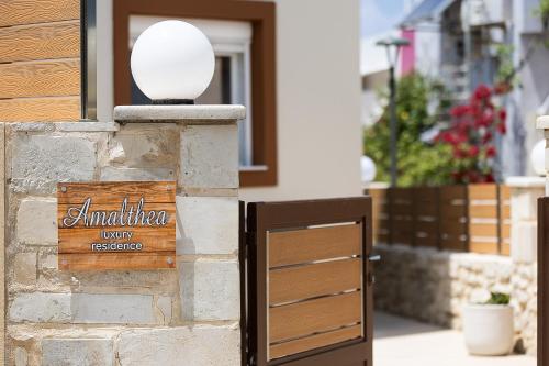 Amaltheia Luxury Residence في مدينة ريثيمنو: علامة على جدار من الطوب مع منزل