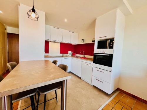 une cuisine avec des armoires blanches et une table avec des chaises dans l'établissement Quiberon - 2 pièces cosy à 20m de la plage avec parking - FR-1-478-247, à Quiberon