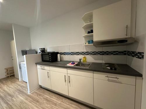 a small kitchen with a sink and a microwave at Neubau Monteurwohnung für 2-4 Gäste in Kiel in Kiel