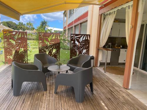 a patio with chairs and a table on a deck at Village Kawann accès plage in Folle Anse