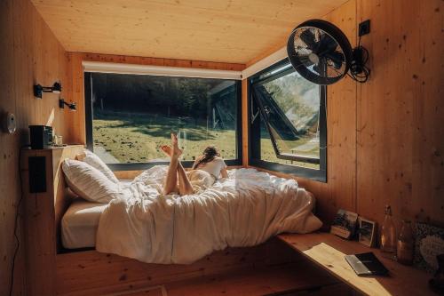 una donna sdraiata a letto in una piccola casa di Parcel Tiny House Barroux, entouré par les lamas près du Mont Ventoux a Le Barroux